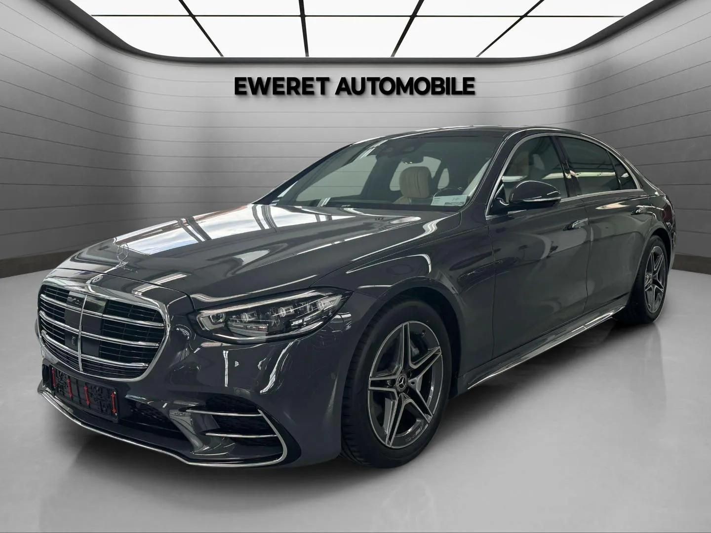 Luxury black sedan in a modern showroom with 'EWERET AUTOMOBILE' sign.